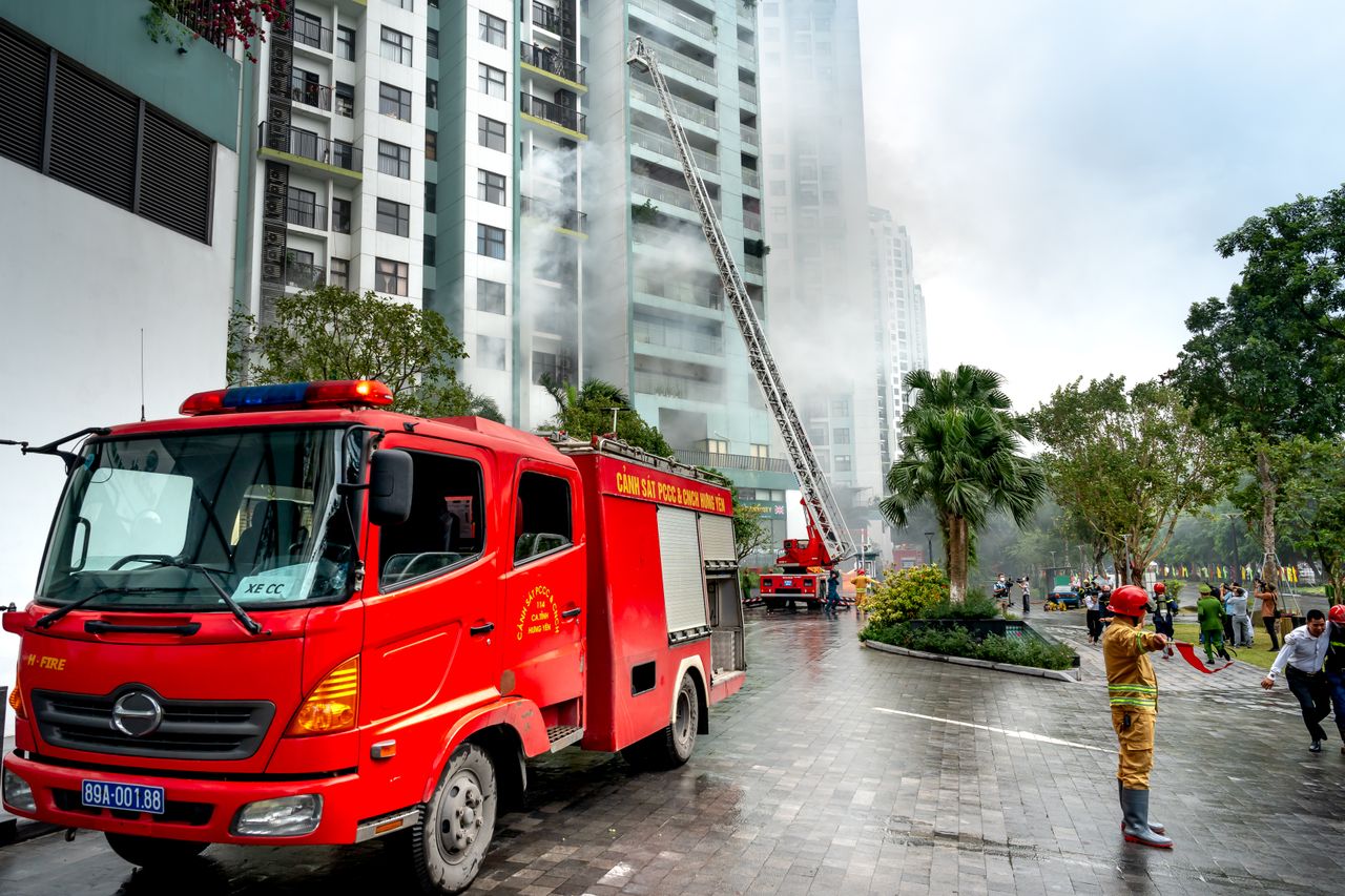 Home Firefighters extinguishing smoke from a building with fire trucks in an urban area.
