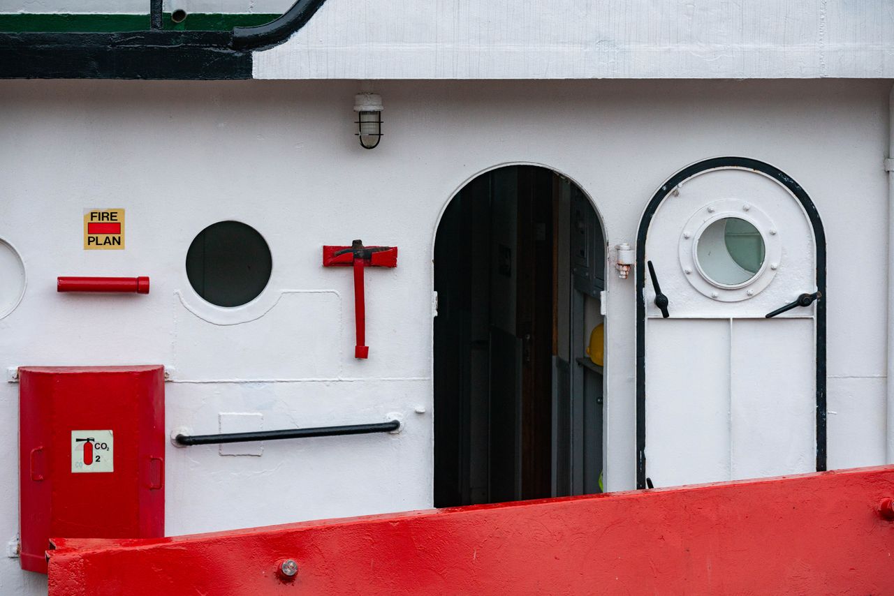 Services Close-up of a marine vessel's exterior showing portholes and safety equipment.